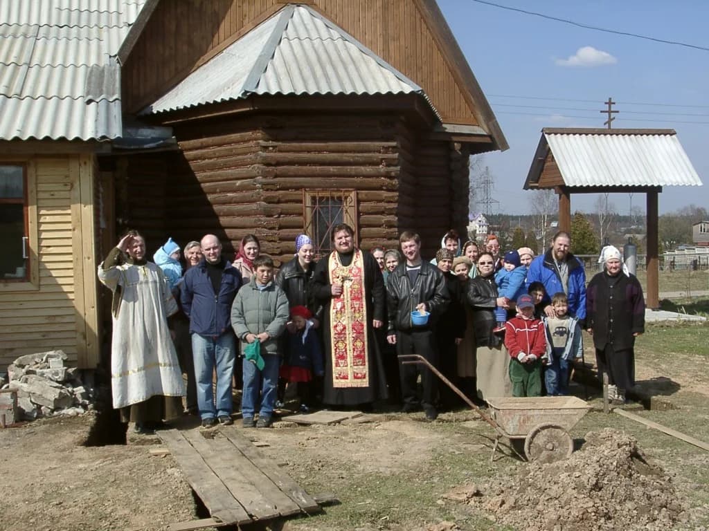 Прихожане со священником у деревянного храма